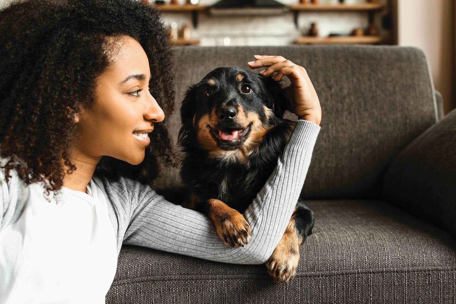 woman with small dog on gray sofa smiling